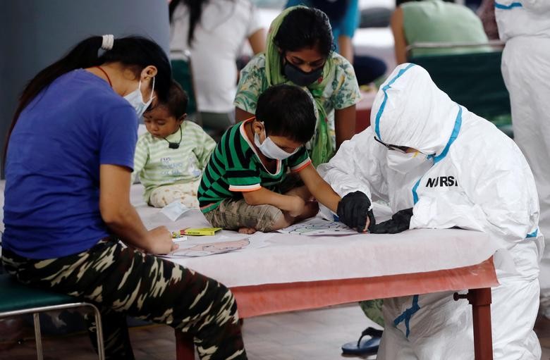 A medical worker helps a boy to draw inside a care centre for the coronavirus disease (COVID-19) patients at an indoor sports complex in New Delhi. REUTERS/Adnan Abidi